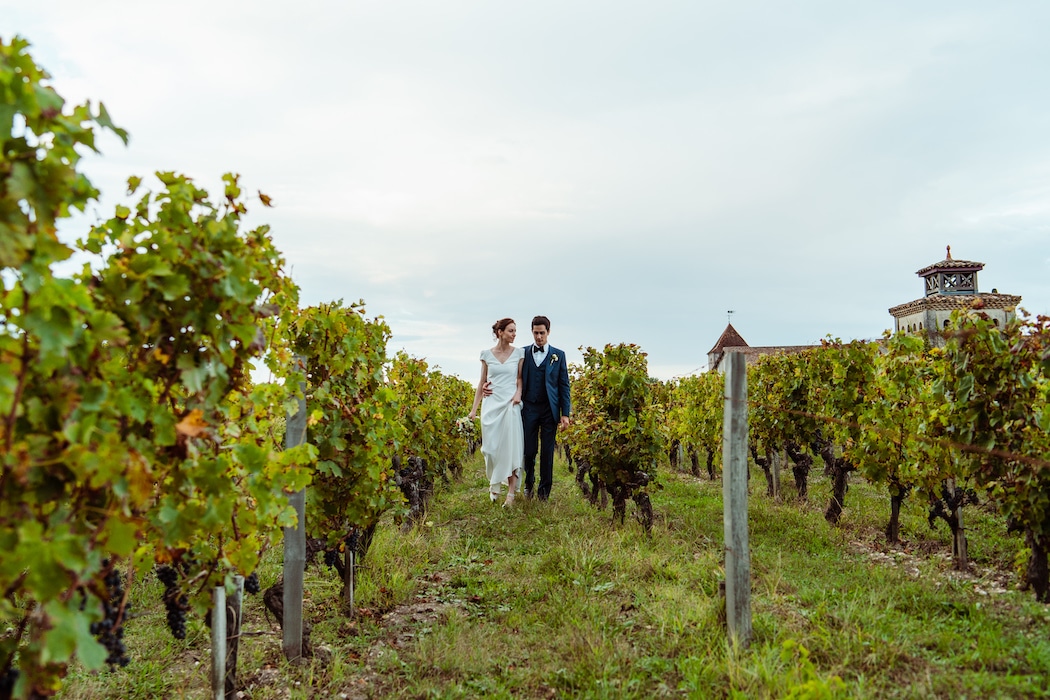 Couple de mariés marchant dans les vignes.
