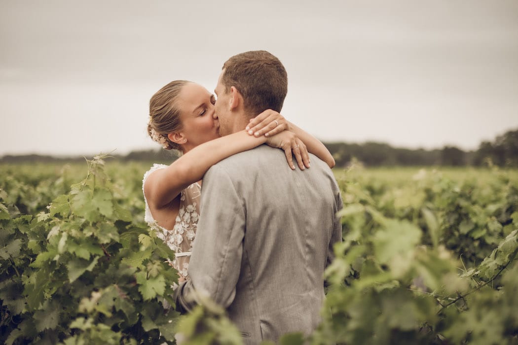 Couple de mariés qui s'embrasse au milieu des vignes